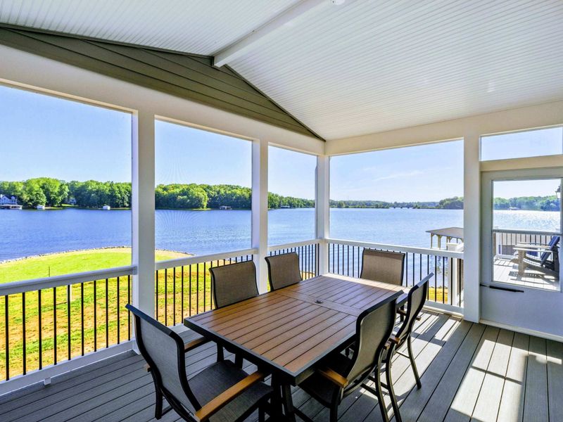 Screened-in porch with dining area and panoramic lake views, perfect for enjoying meals outdoors