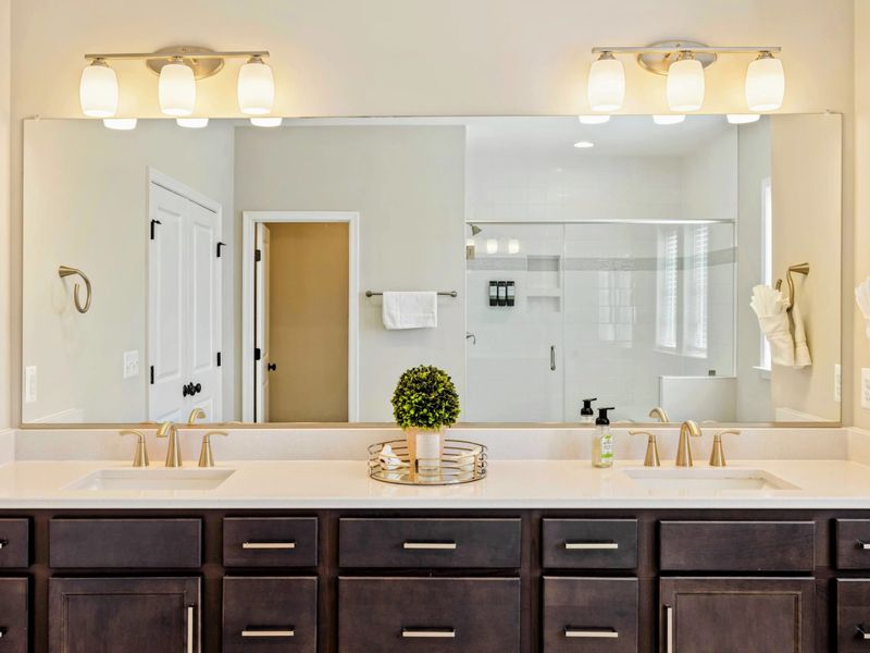 Modern en-suite bathroom with a large mirror, double vanity, and elegant lighting