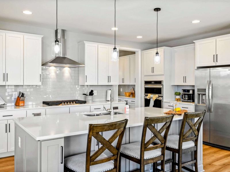 Our modern kitchen is fully equipped with stainless steel appliances, a spacious island with seating, and elegant lighting for a delightful culinary experience.