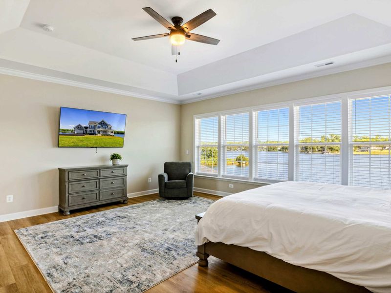 Elegant Primary Bedroom with lake views, a ceiling fan, and a wall-mounted TV