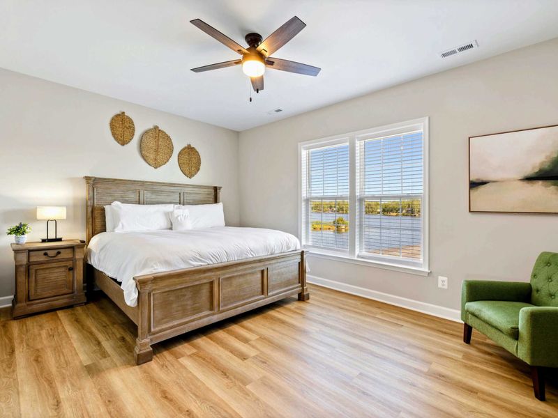 Spacious bedroom with a king-size bed, ceiling fan, and large windows offering lake views