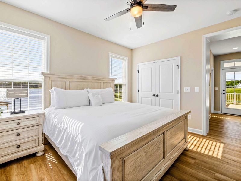 Serene bedroom with a king-size bed, ceiling fan, and beautiful natural light from large windows