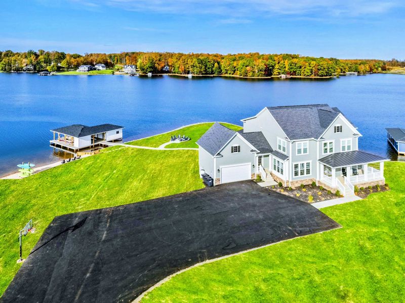 A spacious lakefront property featuring a private boathouse, fire pit area, and plenty of room for recreation and relaxation