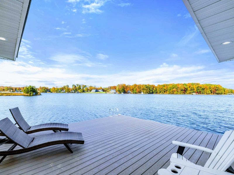 A serene lakeside deck with Adirondack chairs and loungers, perfect for relaxing and enjoying panoramic water views