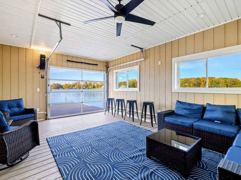 A cozy, enclosed lakeside lounge with comfortable seating, a bar area, and panoramic water views