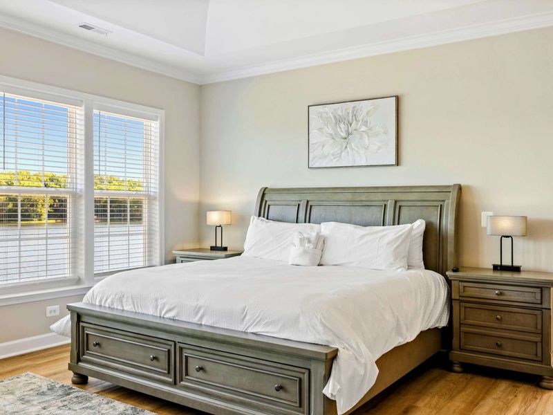 Elegant Primary Bedroom with lake views, a ceiling fan, and a wall-mounted TV