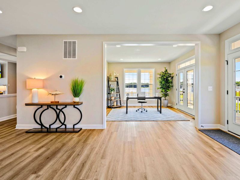 Bright and welcoming entryway leading to a stylish home office with large windows and lake views