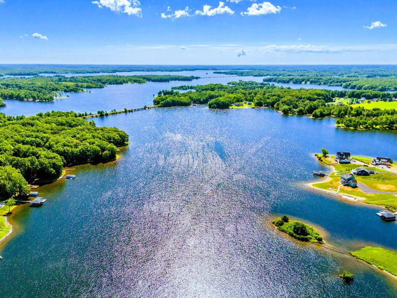 Expansive aerial view of a serene lake surrounded by lush forests and beautiful waterfront homes