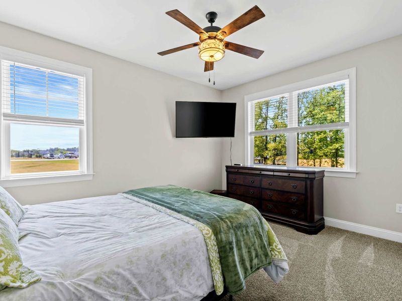 Bedroom 2 - Bed framed by two double-hung windows with sweeping views beyond, ceiling fan overhead.