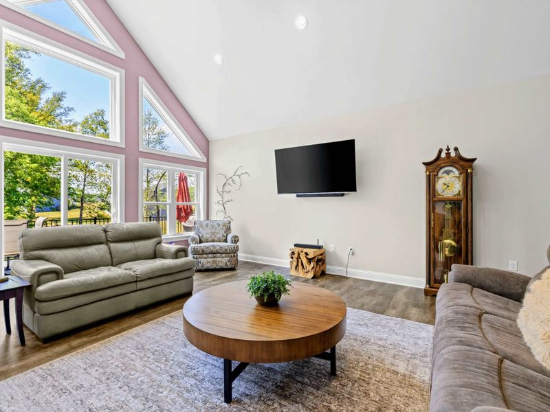 Living Room - A wall-mounted TV and antique grandfather clock anchor a cozy seating arrangement around the round wood coffee table.