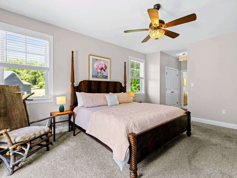 Primary Suite - Bed angle showing the antique dresser, A-frame side window, and an heirloom rocking chair.