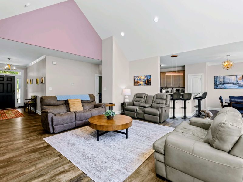 Living Room - Open layout flows from the great room past the front entry through to the dining table beyond.