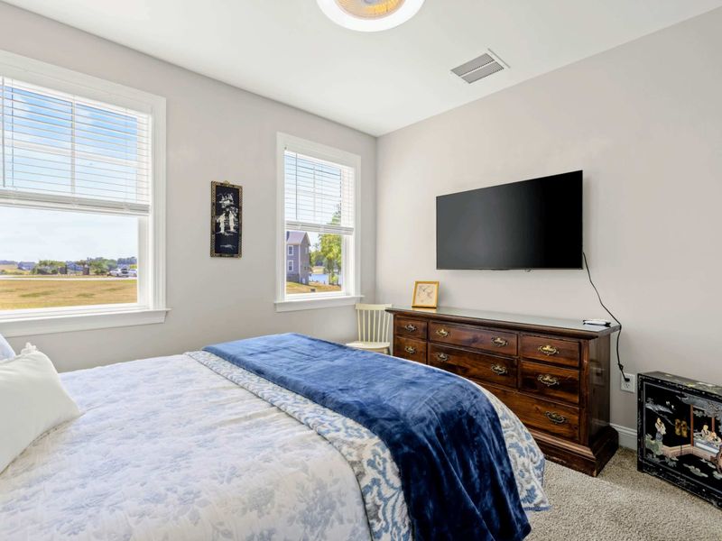 Bedroom 3 - Wall-mounted TV across from the bed, antique dresser, and bright twin double-hung windows.