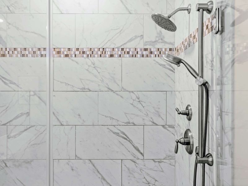 Primary Bathroom - Marble tile, mosaic accent band, and a multi-function shower head set the spa tone.