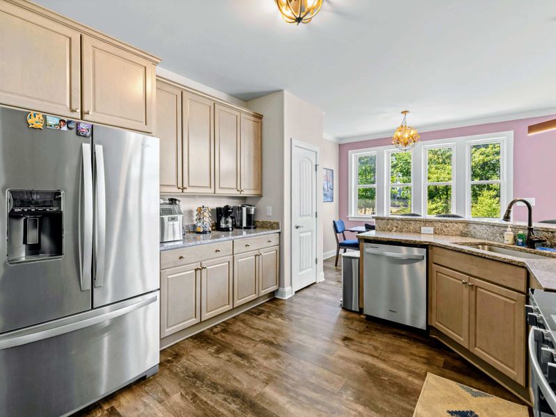 Kitchen - Sink and dishwasher tucked beneath the bay of windows, with the dining area framed by the pink peak gable.
