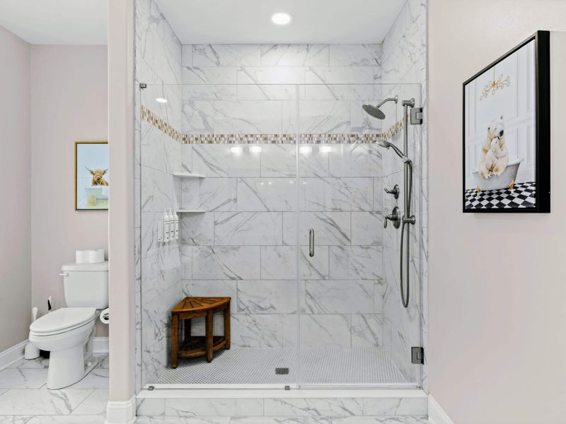 Primary Bathroom - Walk-in shower with marble-look tile, mosaic accent stripe, and glass enclosure.