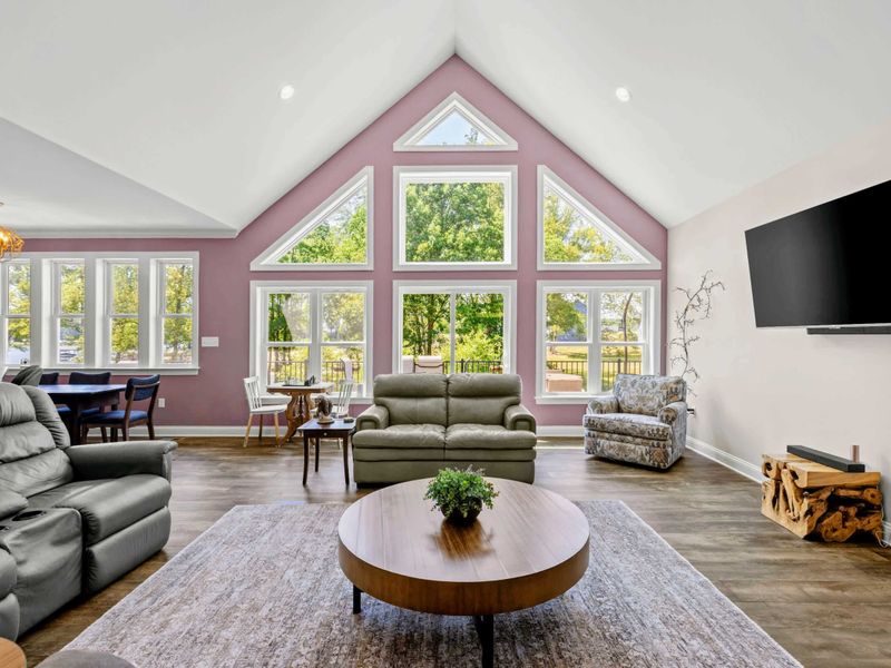 Living Room - The pink-accented gable peak frames floor-to-ceiling windows that pull the lake view inside, with recliners ready for movie night.