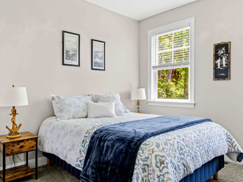Bedroom 3 - Anchor-detailed brass lamps frame the bed with paired framed prints above.