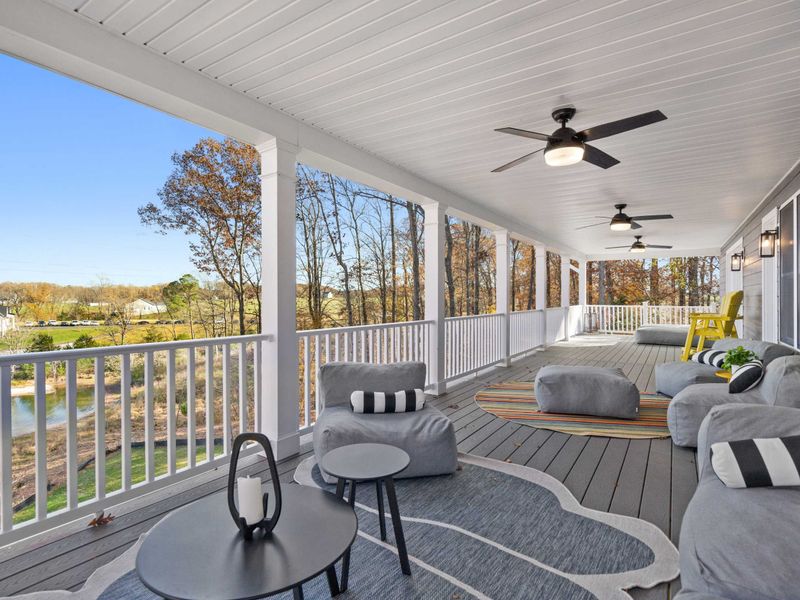 Wraparound Porch - Multiple seating areas stretch across the covered deck, with lake views peeking through the trees.