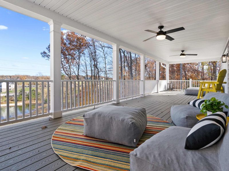 Lake View Porch - The covered deck opens to panoramic views of Lake Anna, with lounge seating and a yellow Adirondack chair.