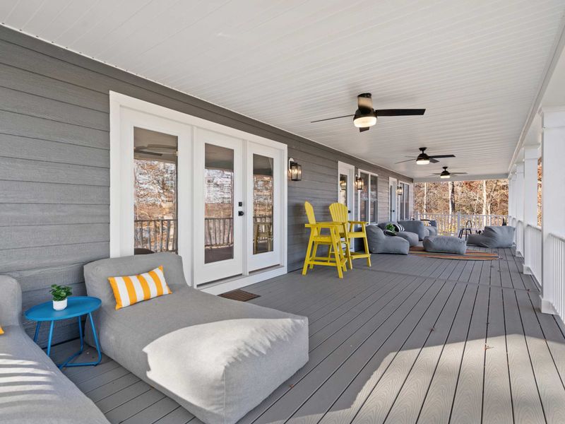 Full Deck View - The expansive covered porch stretches the length of the home, with multiple seating zones and lake glimpses.