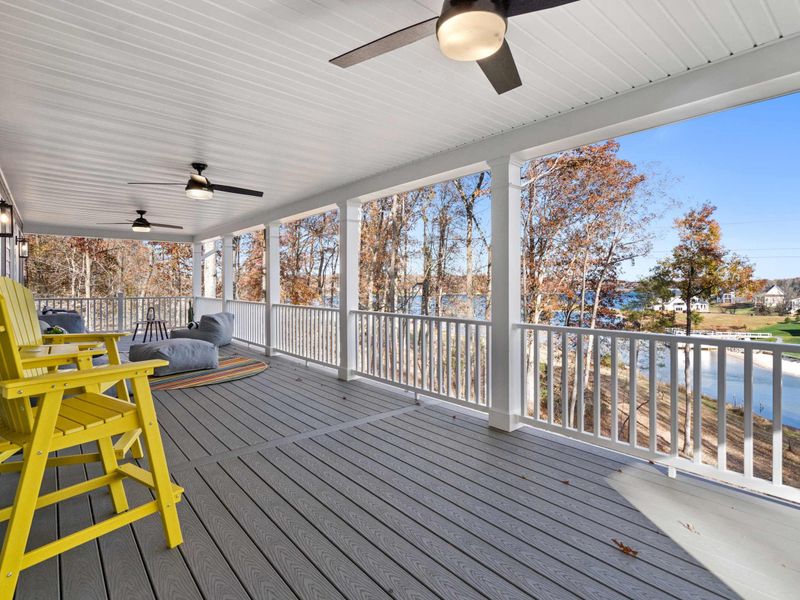 Lakeside Deck - The porch wraps around to a view of the water, with comfortable seating and a yellow bar chair for a higher vantage point.