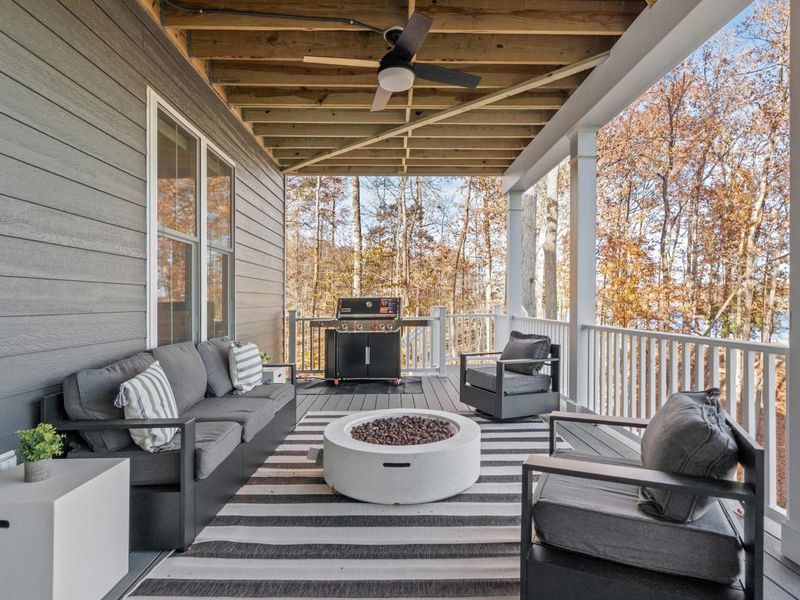 Fire Pit Lounge - Comfortable seating around a white fire pit on the lower covered deck, with the propane grill steps away.