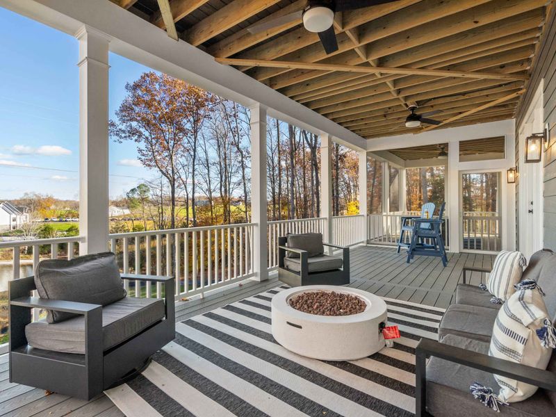 Lower Deck Fireside - Swivel chairs and a sofa surround the fire pit, with lake views through the trees and the neighborhood beyond.