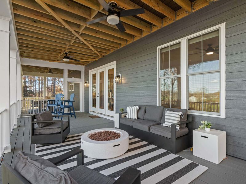 Outdoor Living - The lower deck lounge with a fire pit, striped rug, and French doors leading back inside.