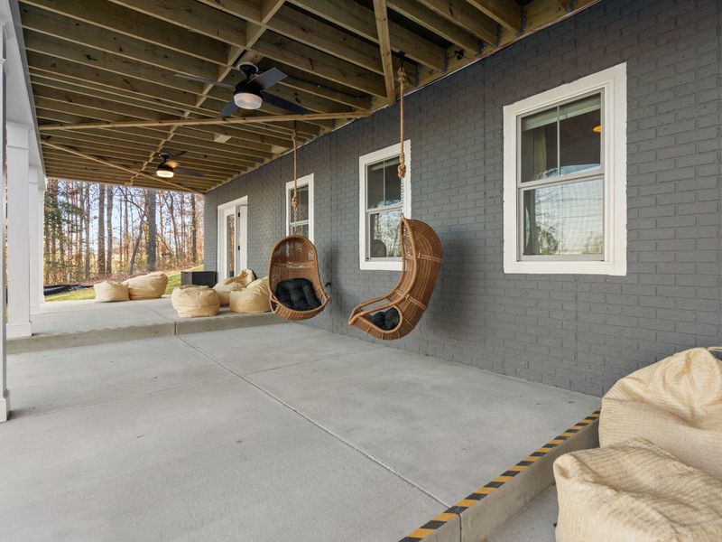 Lower Patio Hangout - Hanging rattan swing chairs and oversized bean bags line the ground-level patio beneath the deck.