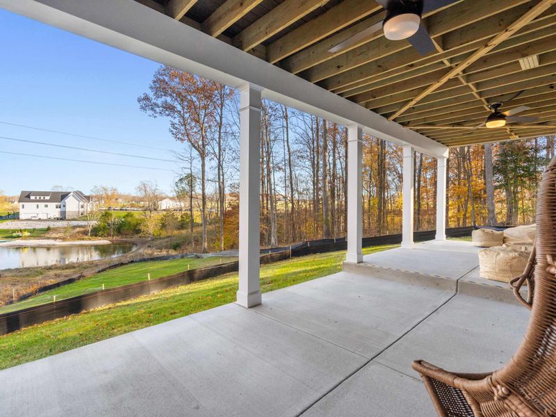 Patio Swings - A pair of wicker egg swings and bean bag loungers on the lower patio, with lake views and open green space.