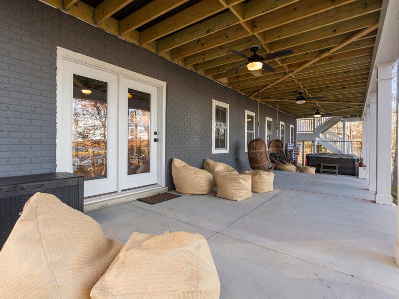 Patio Lounge - Bean bag chairs, hanging swings, and French door access to the lower level, with the hot tub and stairs nearby.