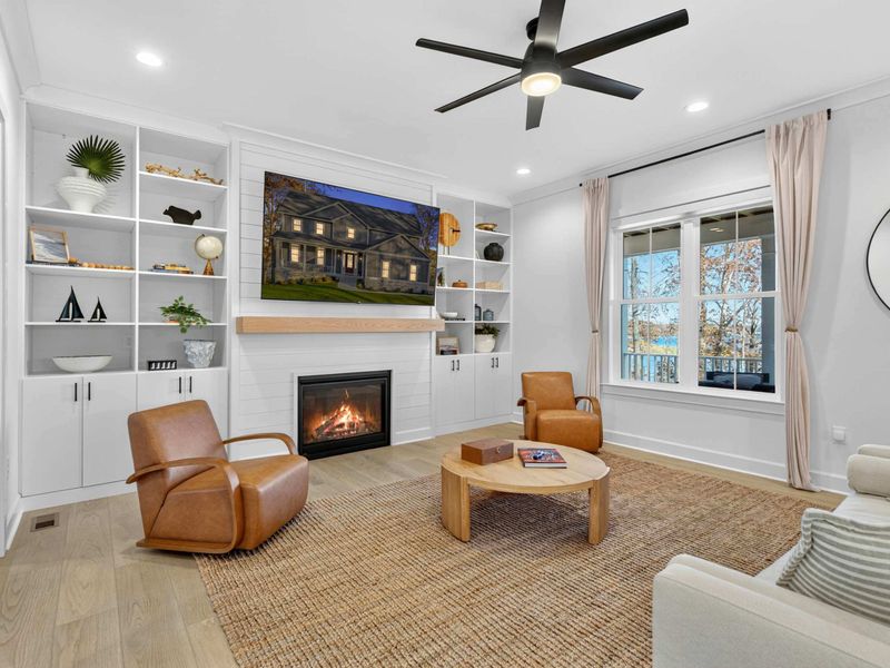 Great Room - Gather around the gas fireplace with built-in shelving, leather chairs, and lake views through the windows.
