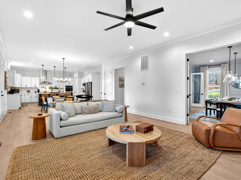 Great Room Overview - A wider view of the open living space, showing the sofa, leather chair, kitchen, and a peek into the dining room.