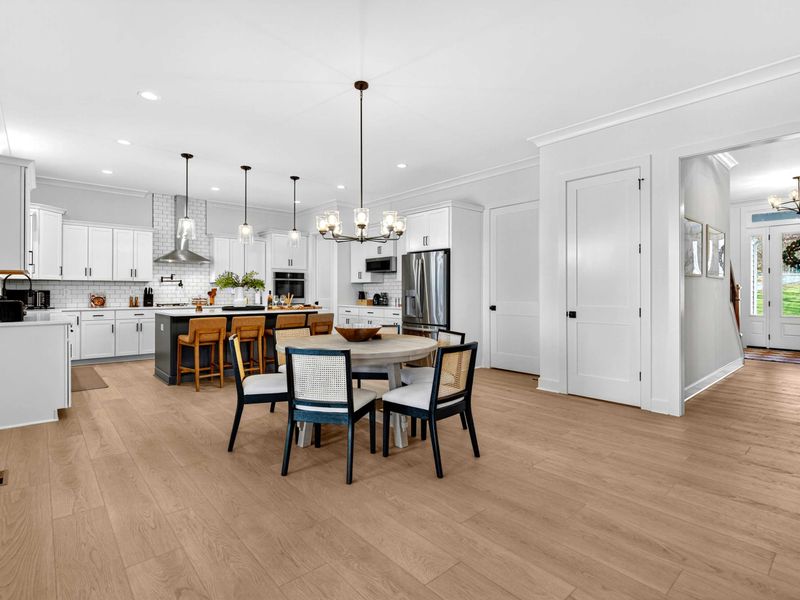 Kitchen and Dining - The open layout connects the round dining table, kitchen island, and pantry, with the front entry hall just beyond.