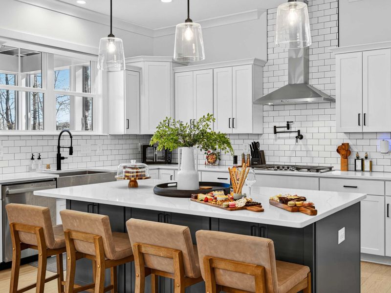 Island Close-Up - A closer look at the island with pendant lighting, a farmhouse sink, and a charcuterie board set for arrival.