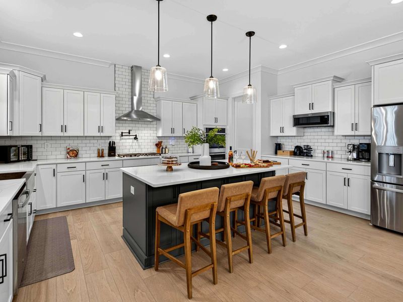 Kitchen Island - Four leather stools line the oversized island, with pendant lights, subway tile, and a charcuterie spread ready to enjoy.