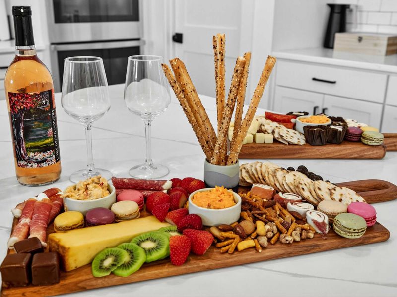 Charcuterie Spread - A curated board with local wine, fresh fruit, cheeses, and sweets on the quartz countertop.