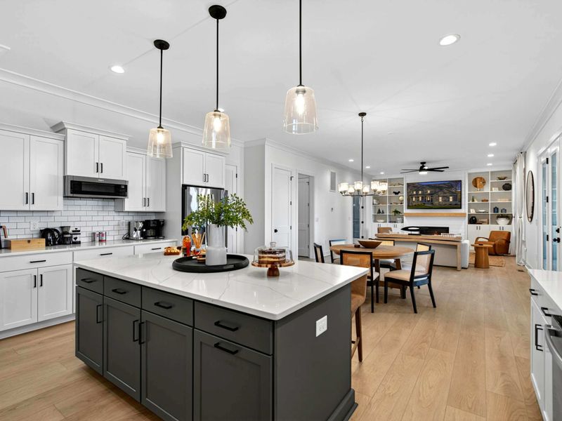 Kitchen to Living - The island and pendants anchor the kitchen, with the dining area, great room fireplace, and built-ins visible beyond.