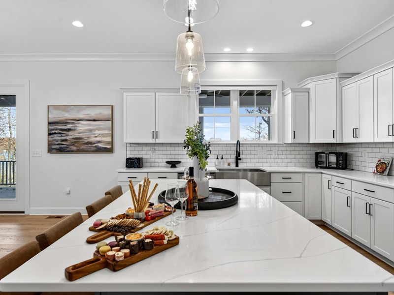 Island and Art - The quartz island with a charcuterie spread, a lakeside painting on the wall, and French doors to the deck.