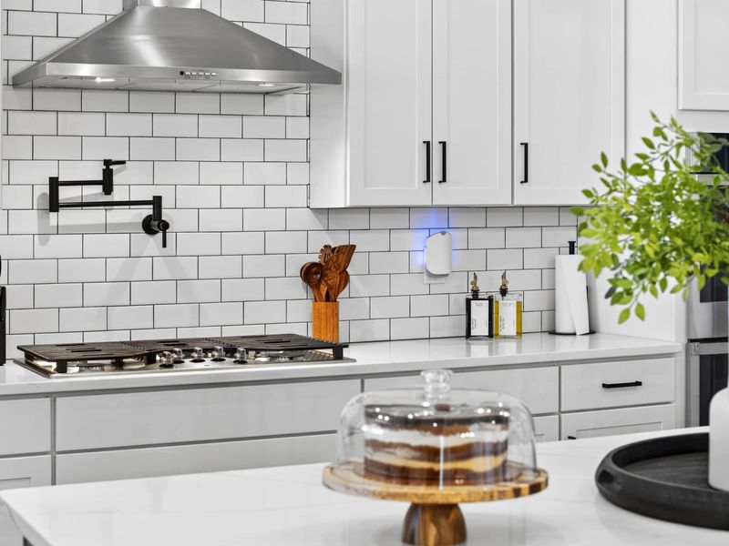 Cooktop Detail - A five-burner gas cooktop with a pot filler, stainless hood, and a full knife block at the ready.