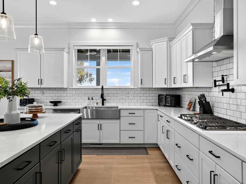 Farmhouse Sink - A stainless steel farmhouse sink with a matte black faucet, subway tile backsplash, and tree views through the window.