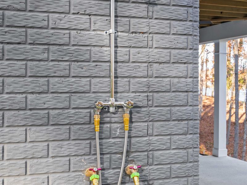 Outdoor Shower Detail - A wall-mounted shower with a handheld sprayer on the lower patio, perfect for washing off sand and lake water.