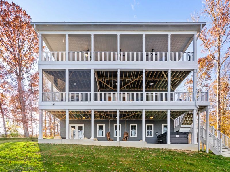 Lakeside Exterior - The three-level rear elevation with wraparound decks on every floor, overlooking the sloped yard and Lake Anna.