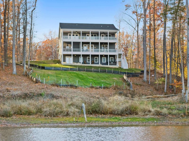 Lake Approach - The home from the water with its terraced yard, lakefront shoreline, and stacked porches.