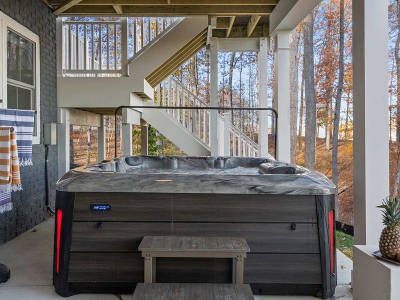 Hot Tub with Cover - The hot tub with its insulated cover in place, tucked beneath the upper deck with stairs leading up.