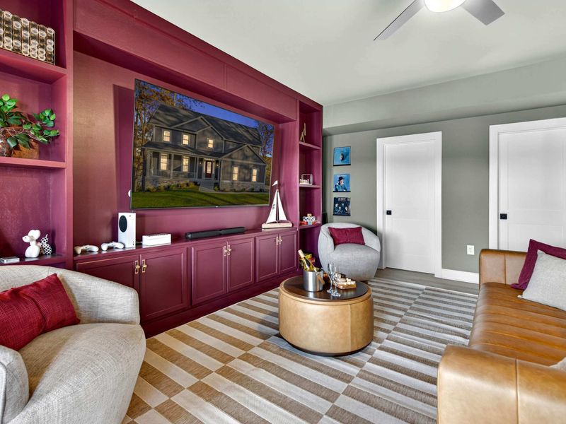 Lower Level Lounge - The full room with its bold entertainment wall, leather seating, and a vaulted ceiling with fan.