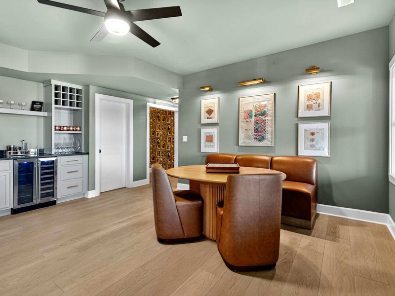 Game Nook and Bar - Leather swivel chairs around a round table, with the wet bar, wine storage, and art-lined walls nearby.