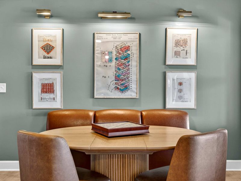 Game Table Art Wall - Framed board game patent prints hang above the leather banquette, with a wooden game box ready for play.