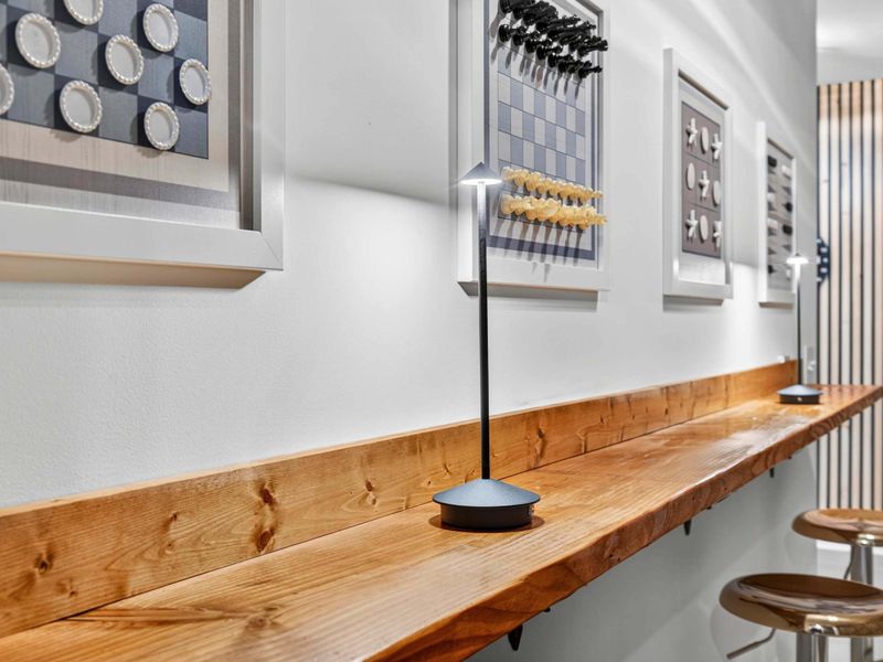 Bar Counter Detail - Live-edge wood, task lamps, and framed checkers and chess sets line the bar counter in the game hallway.